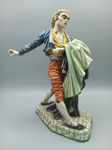 Figura Bandolero Porcelana - Algora Torero en pose dinámica, vestimenta goyesca con chaqueta azul y pantalón rojo, sobre base de piedra.