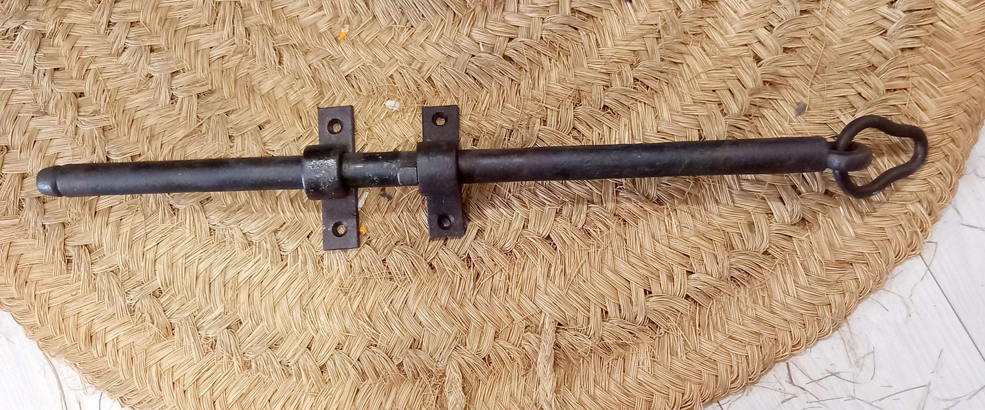 Pestillo de puerta antiguo de hierro forjado con diseño clásico, ideal para decoración rústica y seguridad en puertas de madera.