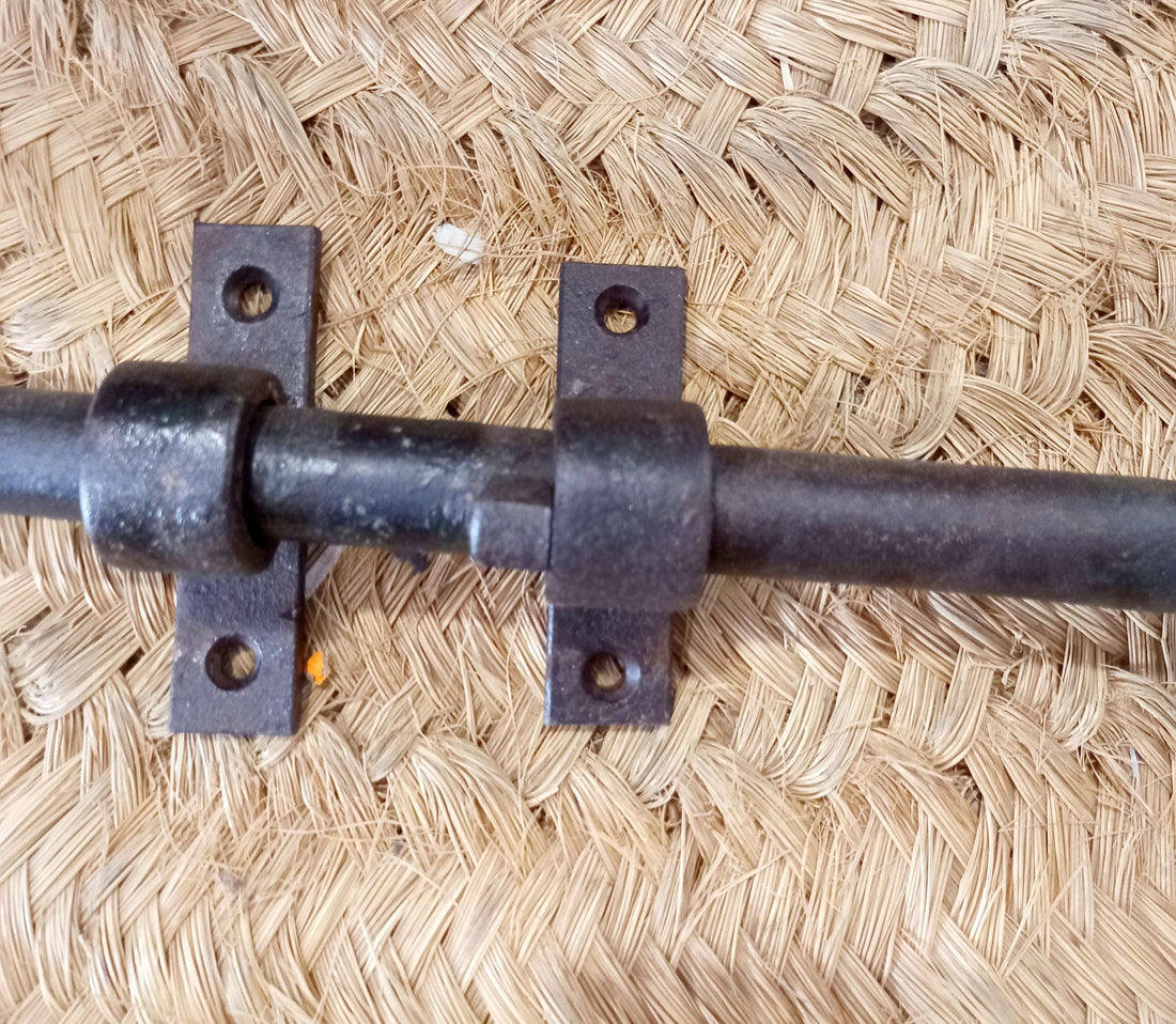 Pestillo de puerta antiguo de hierro forjado con diseño clásico, ideal para decoración rústica y seguridad en puertas de madera.