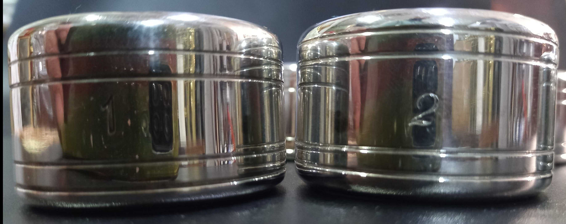 Set de 6 servilleteros de metal plateado con números grabados del 1 al 6, diseño elegante ideal para decoración de mesa en eventos formales.