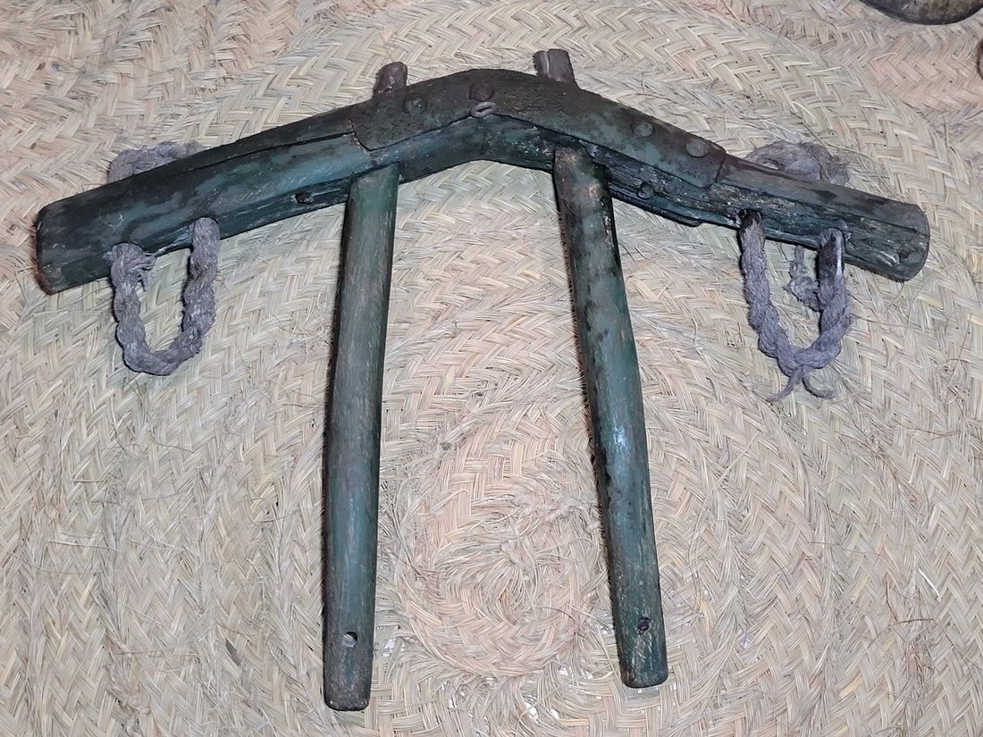 Yugo de costillas en madera de encina con refuerzos de hierro sobre fondo de esparto. Ideal para decoración rústica en hogar o jardín.
