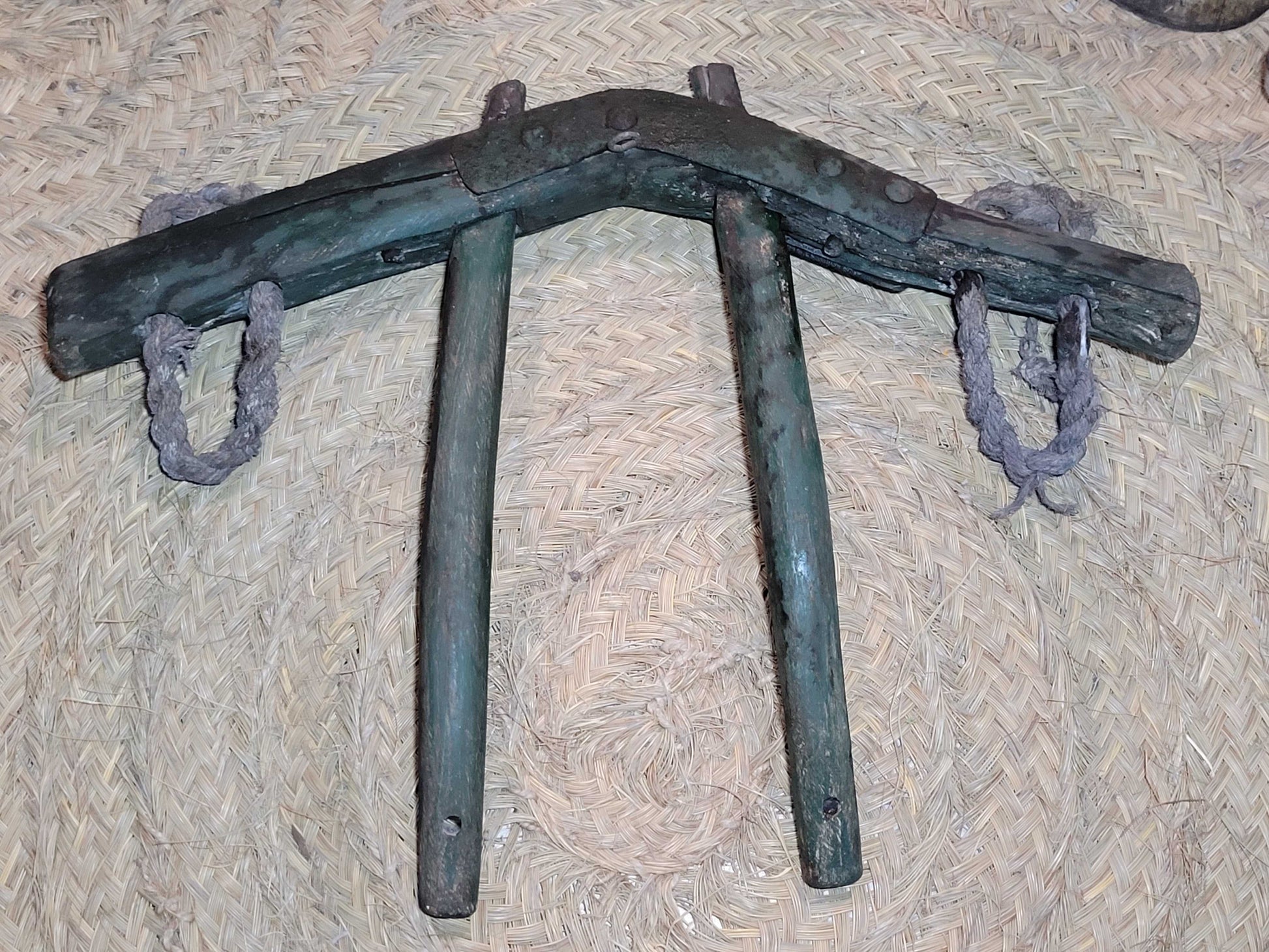 Yugo de costillas en madera de encina con refuerzos de hierro sobre fondo de esparto. Ideal para decoración rústica en hogar o jardín.