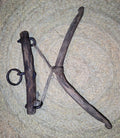 Camal de acebuche y encina con forma en X y argollas metálicas, herramienta tradicional convertida en decoración artesanal de alta calidad.