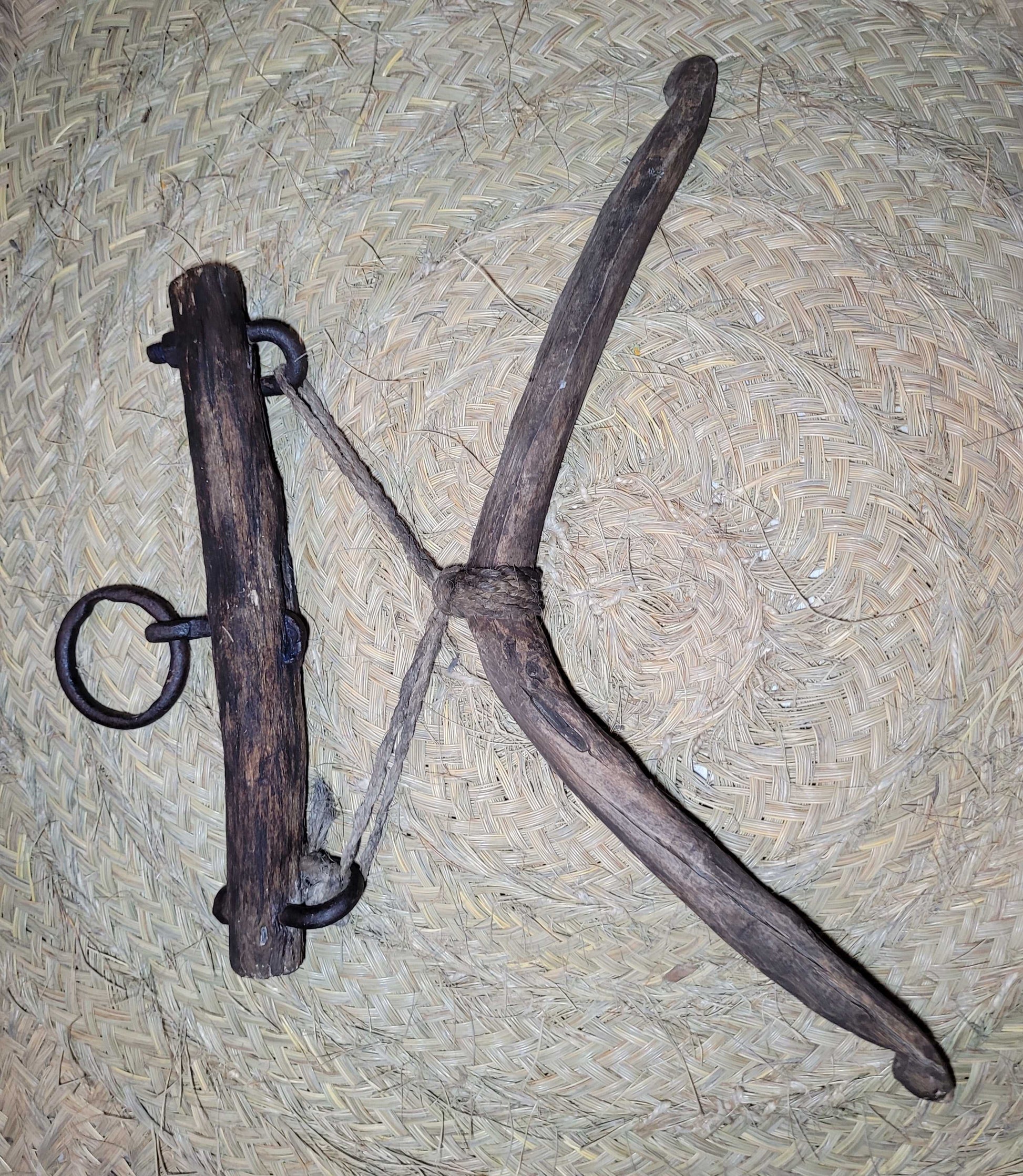 Camal de acebuche y encina con forma en X y argollas metálicas, herramienta tradicional convertida en decoración artesanal de alta calidad.