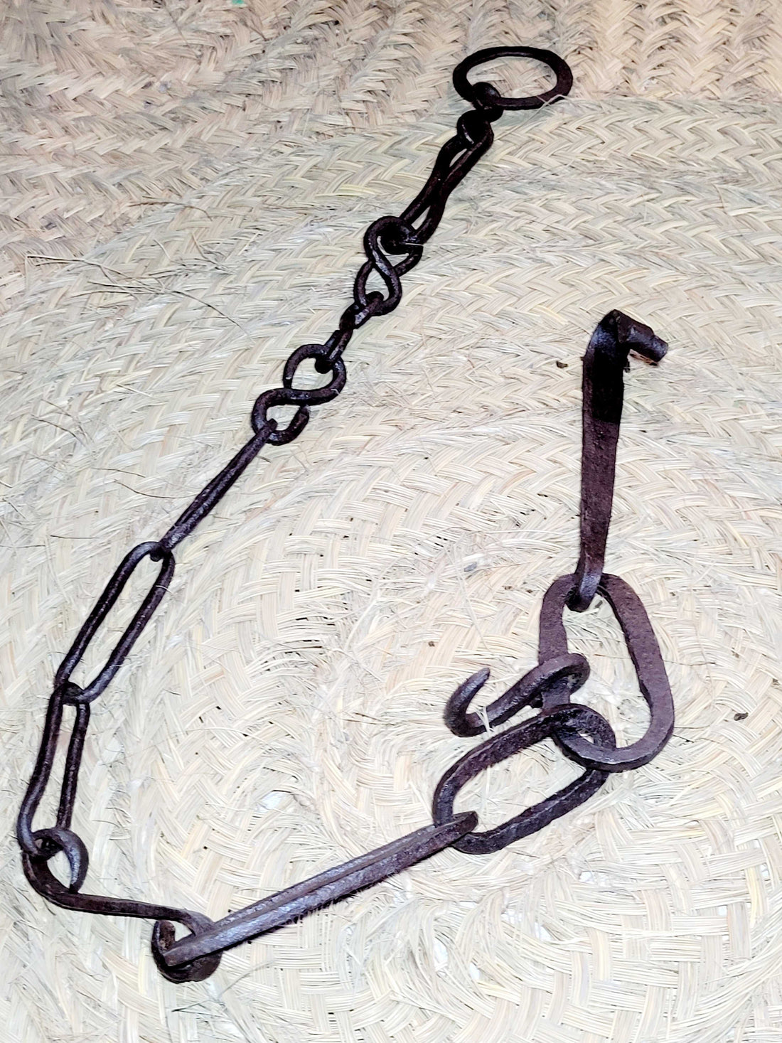 Cadena - Llares de Hierro para Colgar Calderos al Fuego de 125 cm sobre fondo de mimbre. Ideal para decoración rústica en cocinas tradicionales.