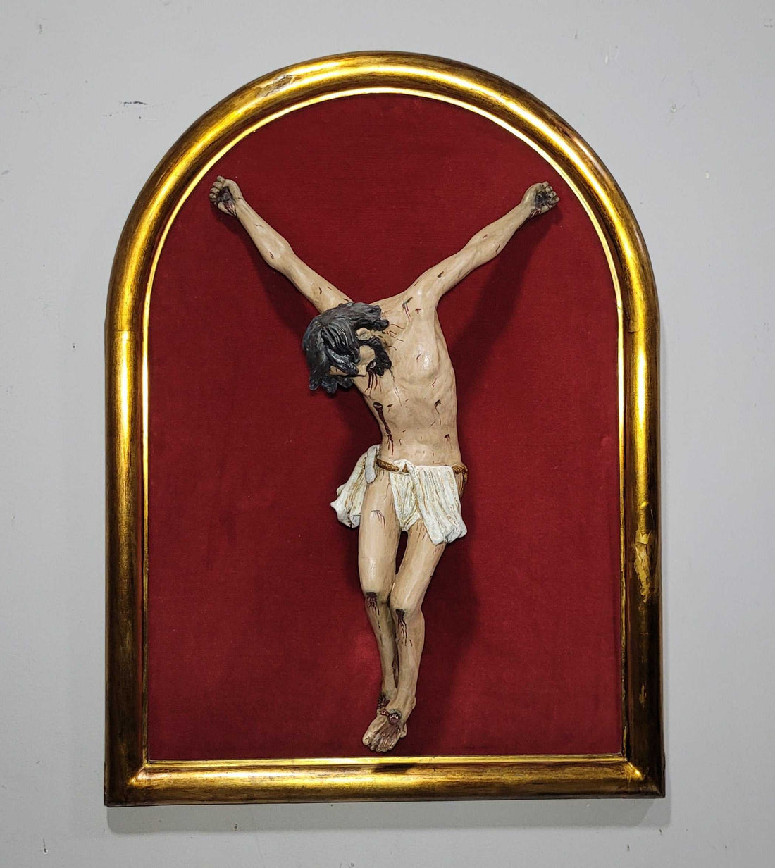 Cristo en terracota sin cruz sobre fondo rojo y marco dorado, ideal para decoración espiritual del hogar. Elegancia y devoción en cada detalle.