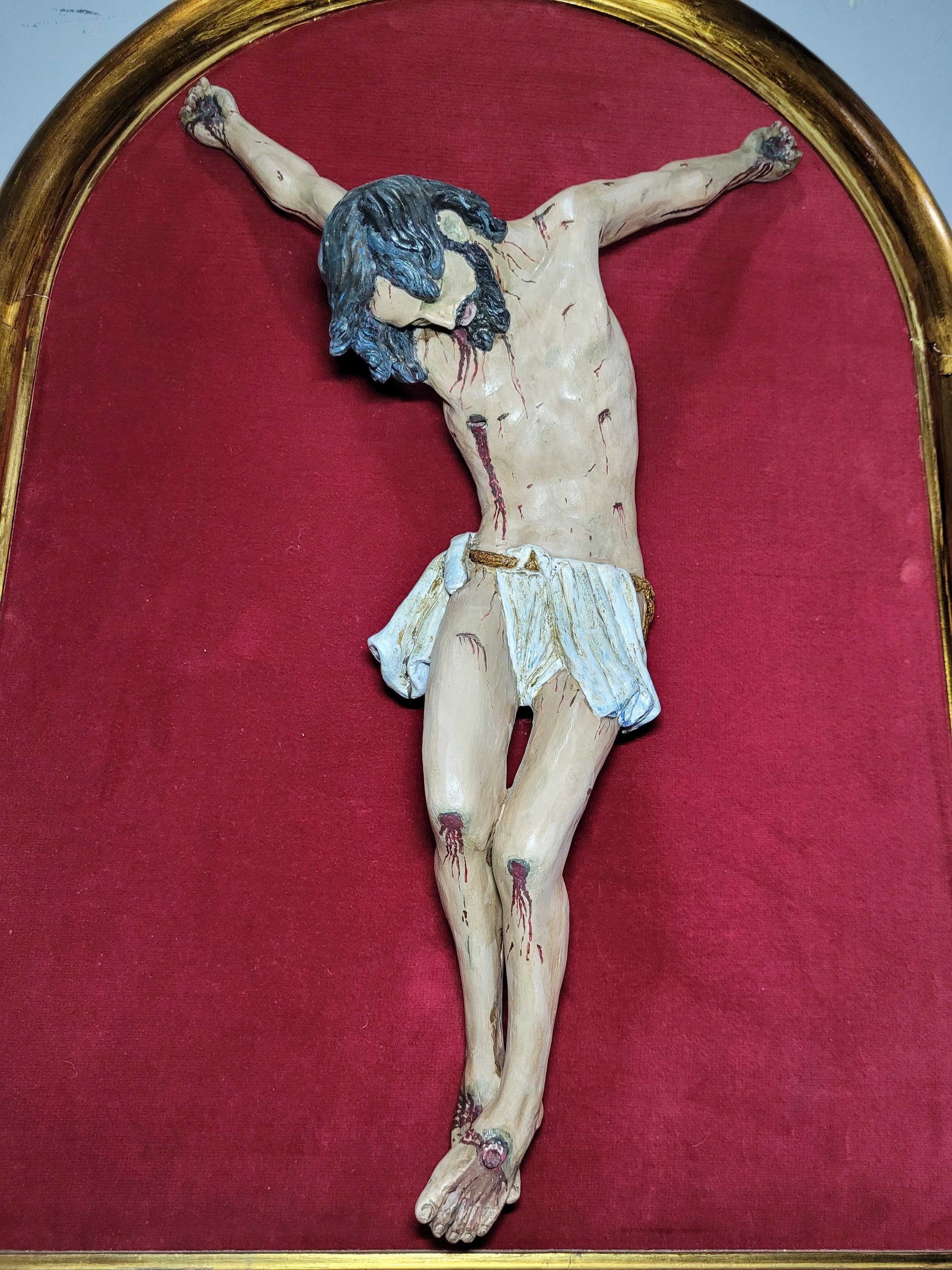 Detalle cercano del Cristo en terracota sin cruz, con acabados realistas y fondo rojo. Decoración religiosa para el hogar con estilo clásico.