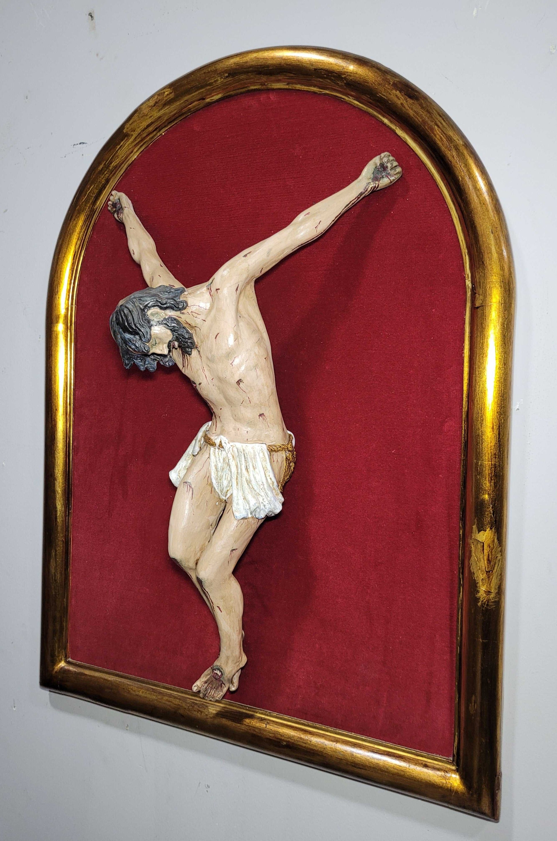 Figura de Cristo en terracota en relieve, montada en marco dorado con fondo rojo. Perfecta para añadir espiritualidad a espacios interiores.
