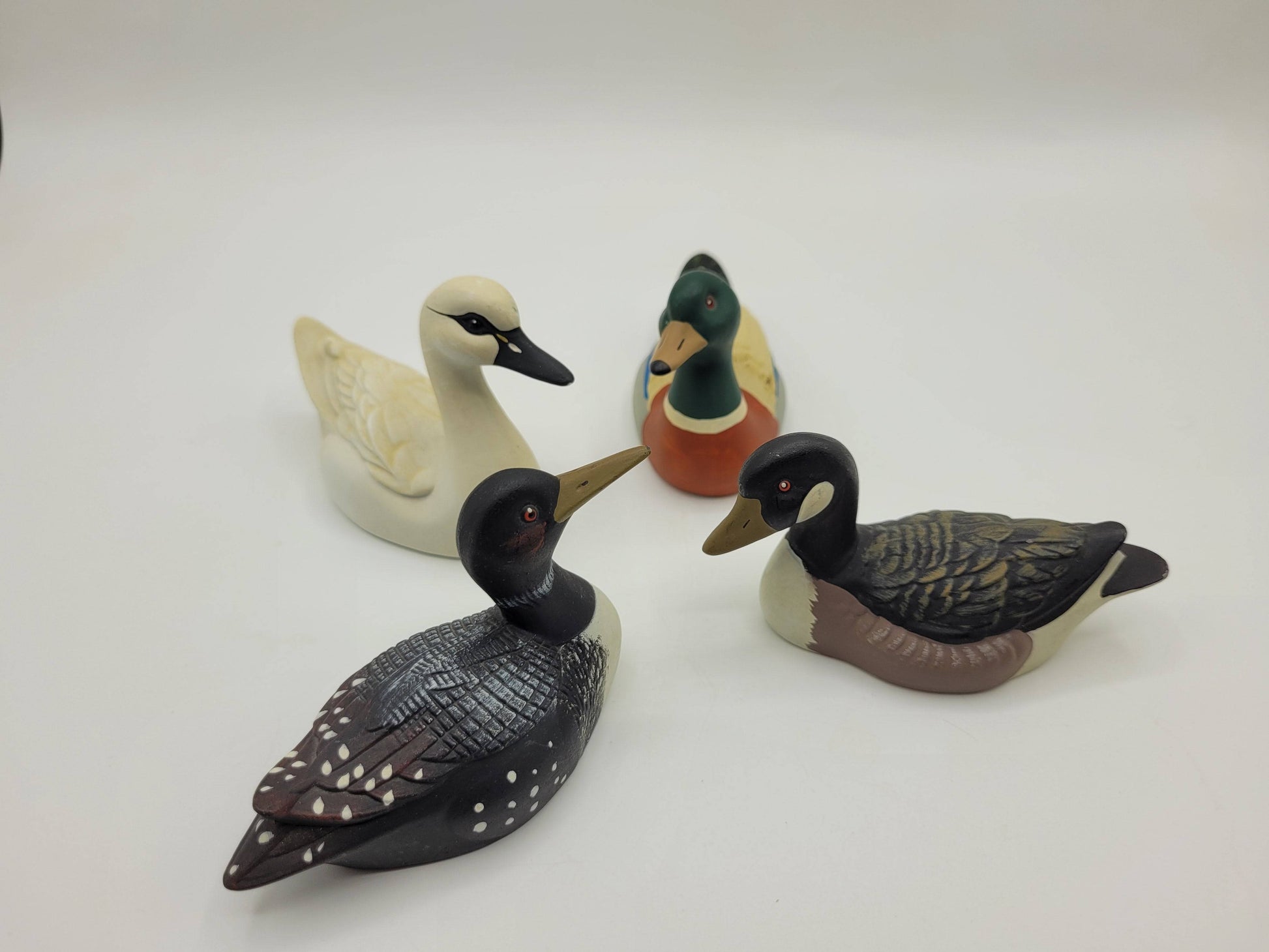 Vista superior de 4 patos de porcelana decorativos en círculo, parte de una colección exclusiva para el hogar. Diseño detallado y acabado de calidad.