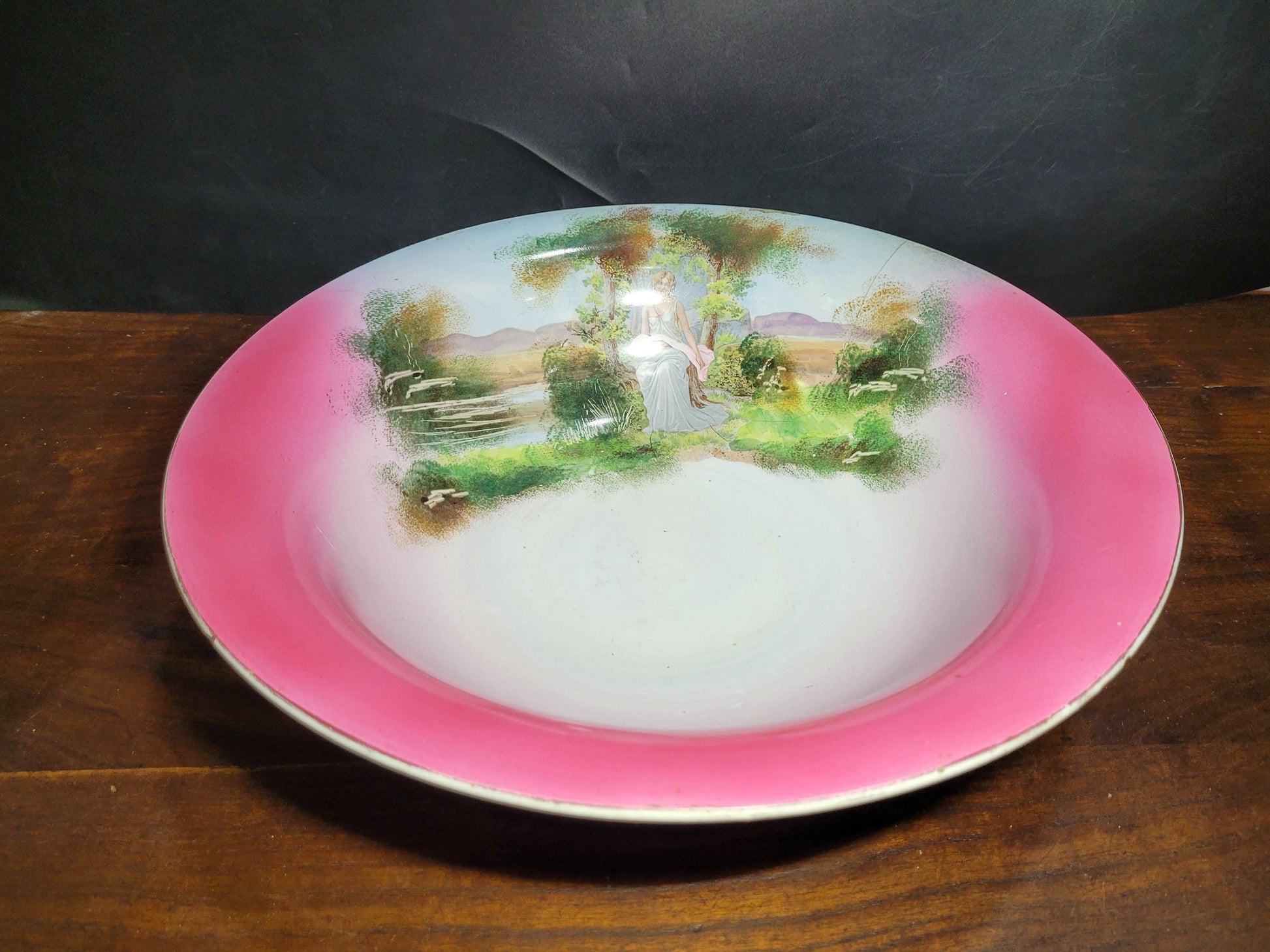  Finamente pintado a mano, este set captura la esencia de la época con un hermoso paisaje que incluye una mujer en un entorno bucólico, reflejando la elegancia y el estilo característico de la porcelana sevillana. 