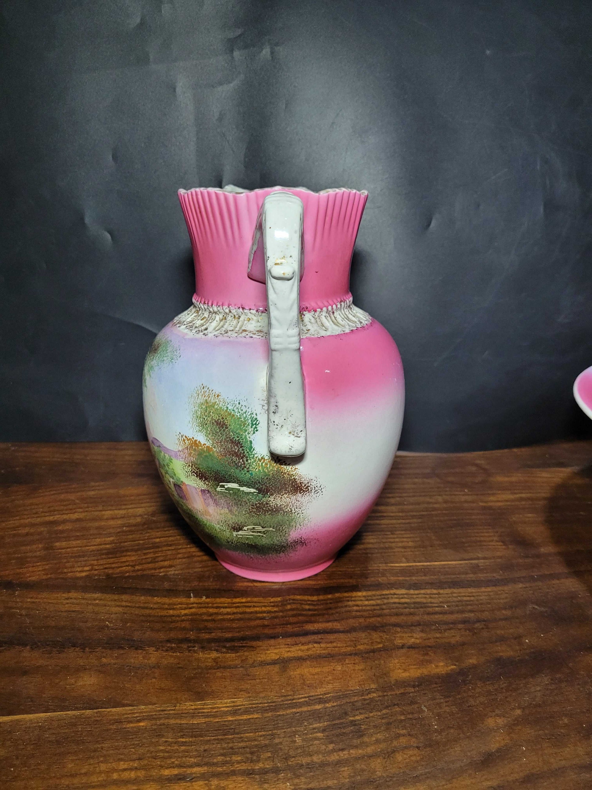 Jarra de porcelana de Sevilla siglo XIX con asa decorativa y paisaje pintado a mano, parte del set de aguamanil y palangana vintage.