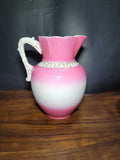 Jarra de porcelana de Sevilla siglo XIX con diseño degradado en rosa y blanco, asa ornamentada y detalles clásicos. Ideal para decoración vintage.