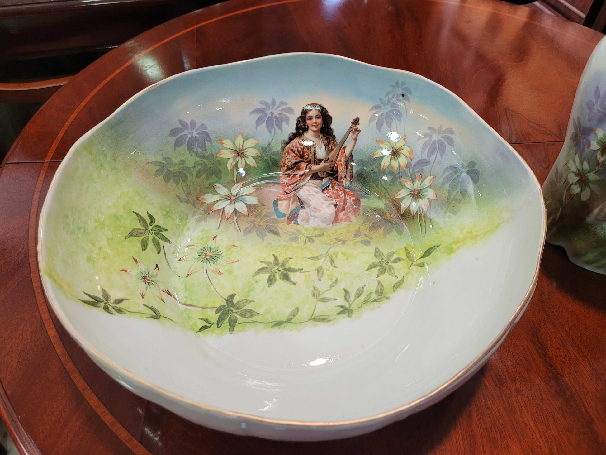 Detalle de la palangana del aguamanil de porcelana Limoges del siglo XIX, pintada a mano con figura femenina en paisaje floral, pieza de colección decorativa.