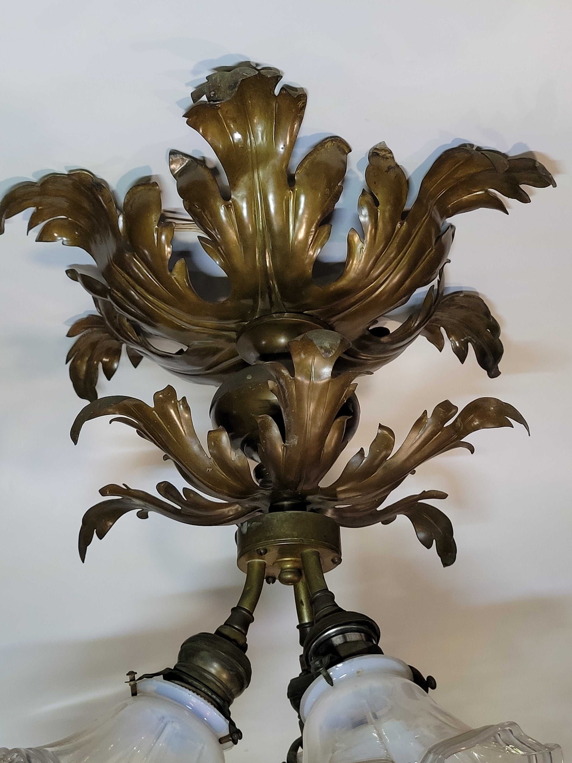 Detalle del soporte metálico con hojas decorativas de lámpara de techo antigua, pieza única de decoración para hogar estilo clásico.