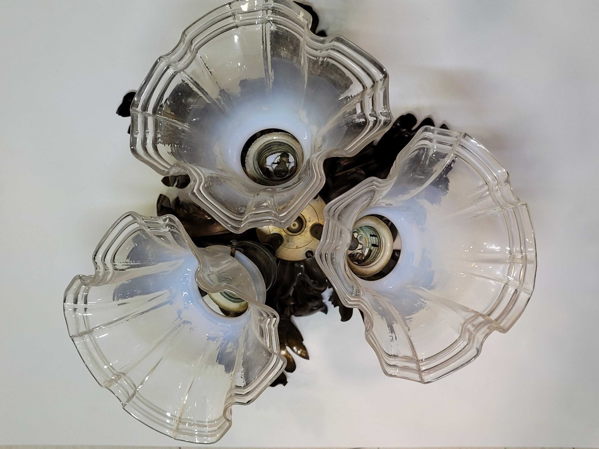 Lámpara de techo vintage con estructura de metal en forma de hojas y tres tulipas de cristal transparente, perfecta para ambientes retro.