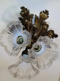 Vista inferior de lámpara de techo antigua de metal con tres tulipas de cristal, diseño floral clásico de los años 50 para decoración de hogar.
