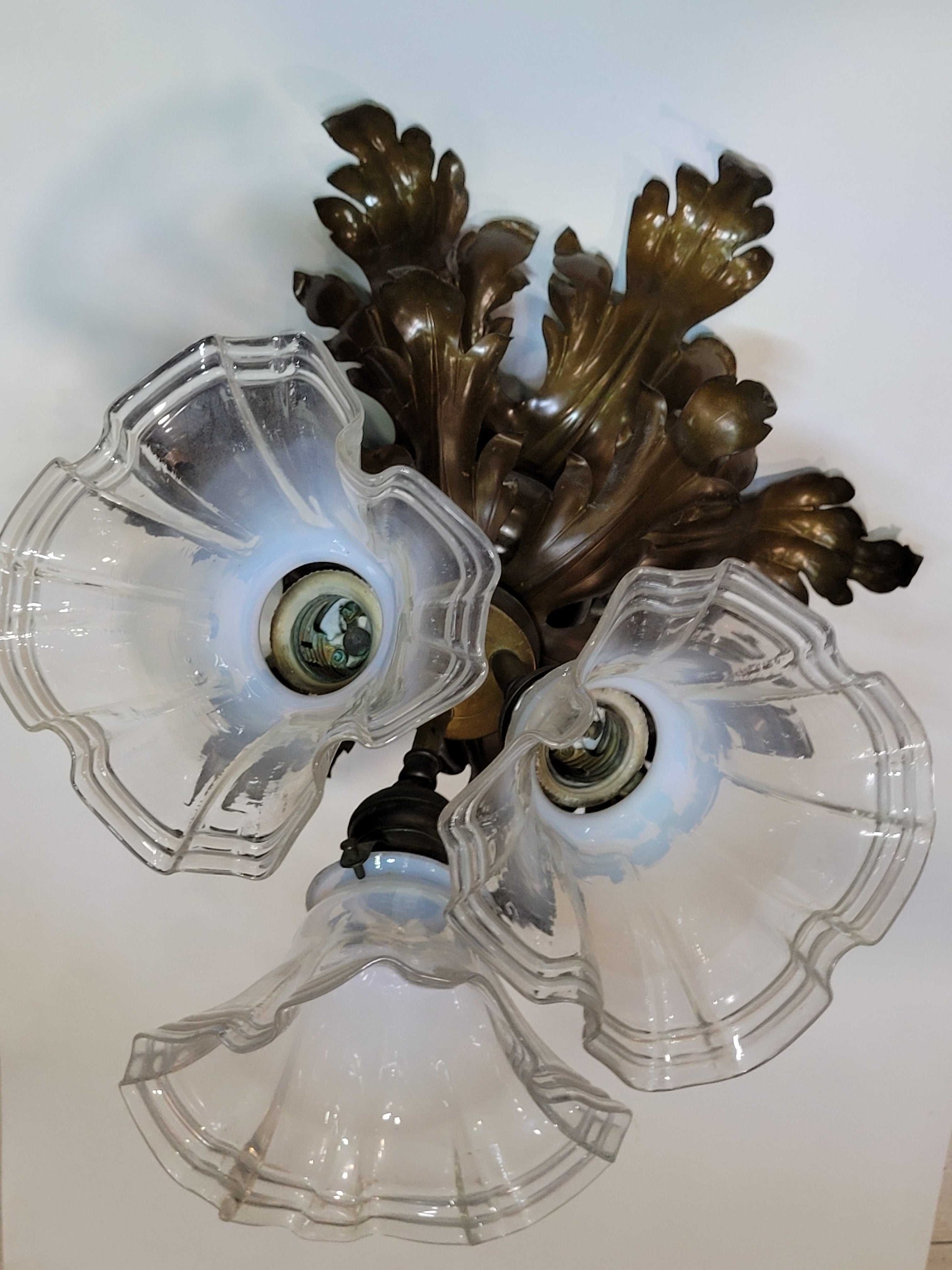 Vista inferior de lámpara de techo antigua de metal con tres tulipas de cristal, diseño floral clásico de los años 50 para decoración de hogar.