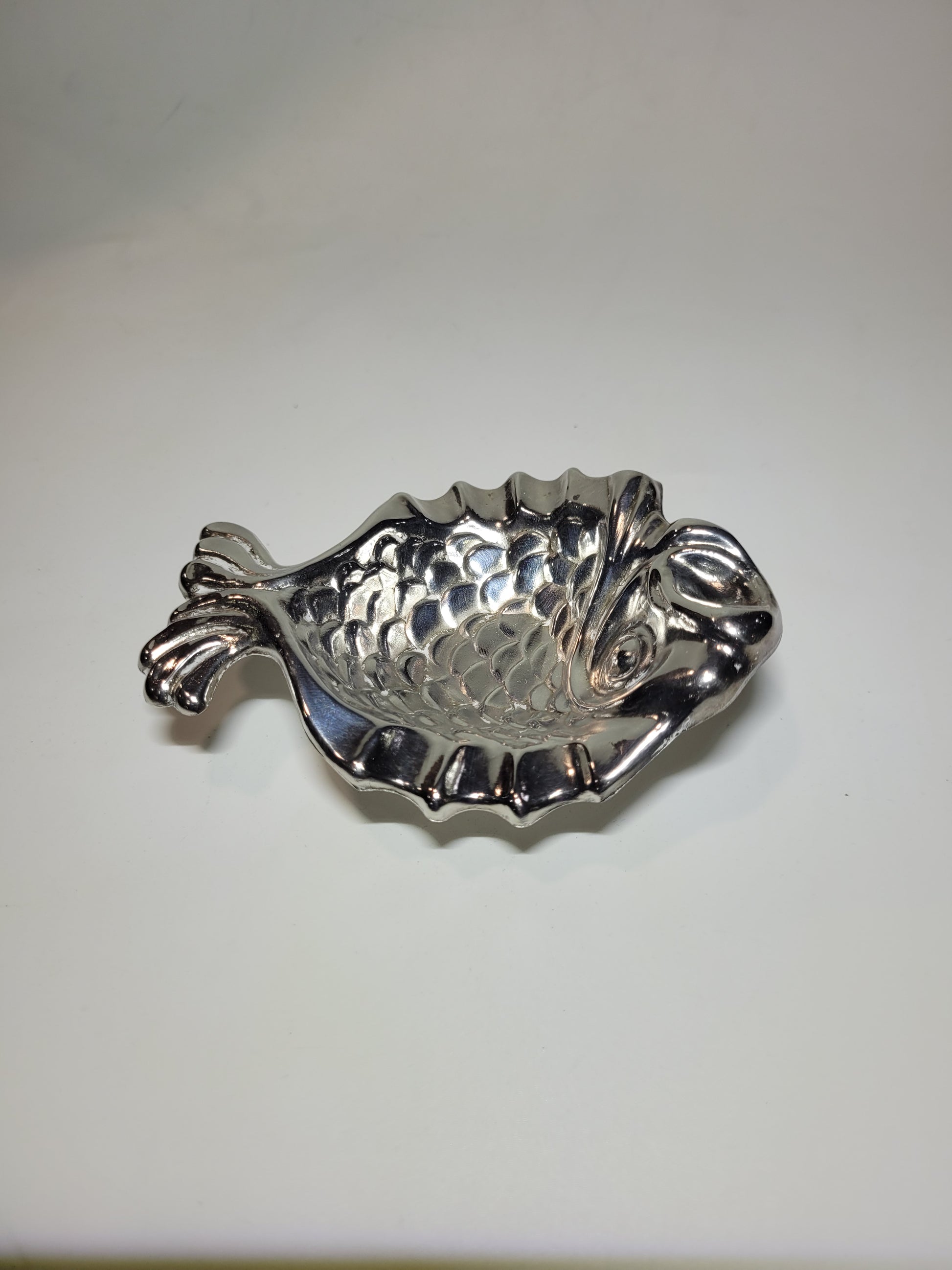 Cenicero de metal plateado en forma de pez con diseño elegante y detalles escamados, ideal para decoración vintage.