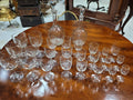 Cristalería antigua de diseño con 6 servicios completos, incluye copas de vino, agua, licor y dos licoreras sobre mesa de madera. Ideal para decoración de mesa elegante.