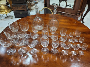 Cristalería antigua de diseño con 6 servicios completos, incluye copas de vino, agua, licor y dos licoreras sobre mesa de madera. Ideal para decoración de mesa elegante.