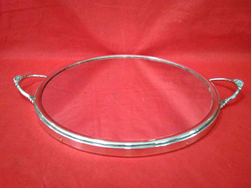 Bandeja redondeada de metal plateado espejada con asas decorativas sobre fondo rojo. Diseño elegante ideal para decoración o servir.