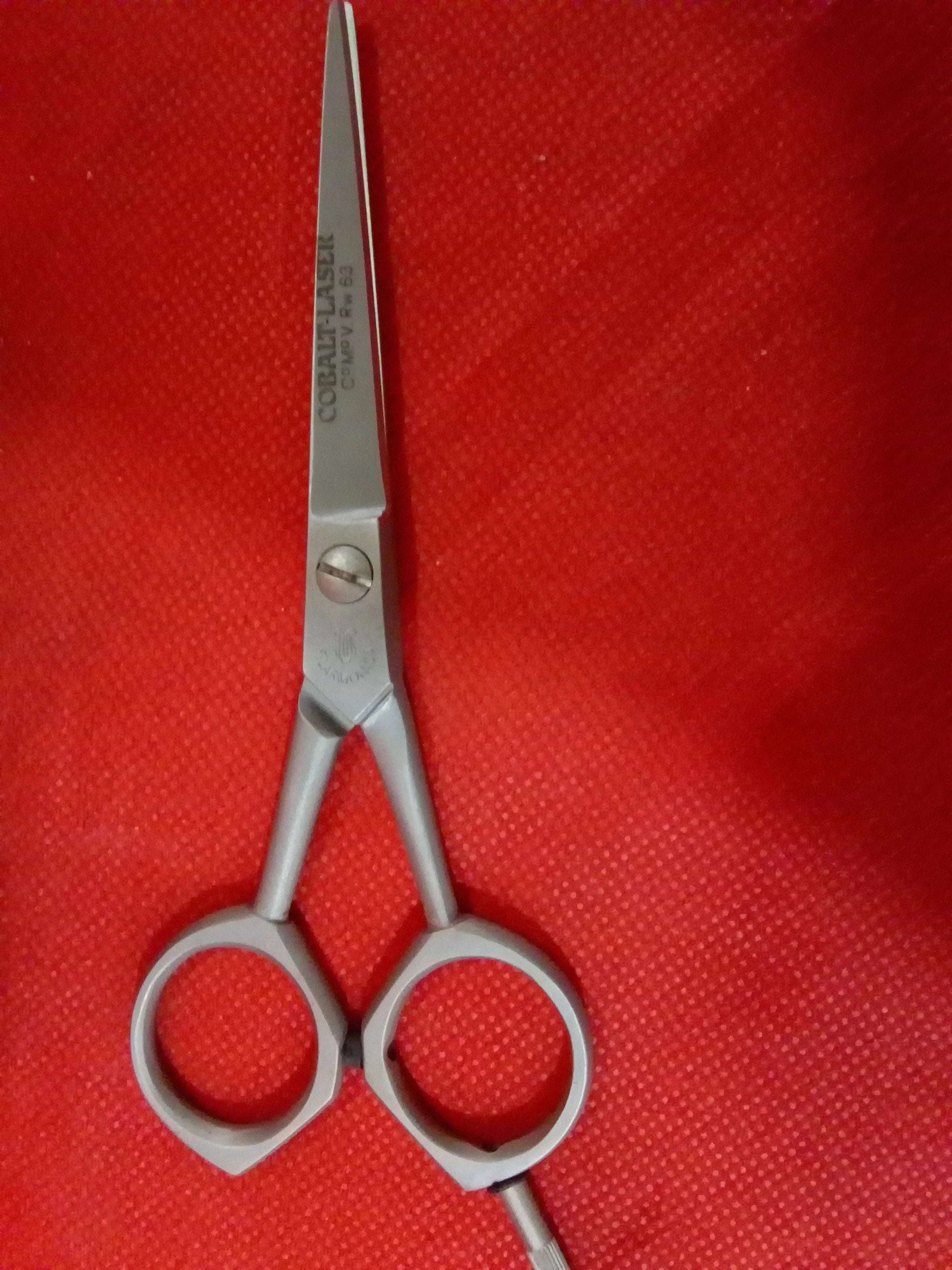Tijera de barbero Filarmónica de cobalto sobre fondo rojo, herramienta vintage de alta calidad ideal para decoración en barberías.