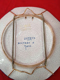 Reverso de plato de cerámica Lufeco pintado a mano con soporte metálico para colgar, ideal para decoración vintage de alta calidad.