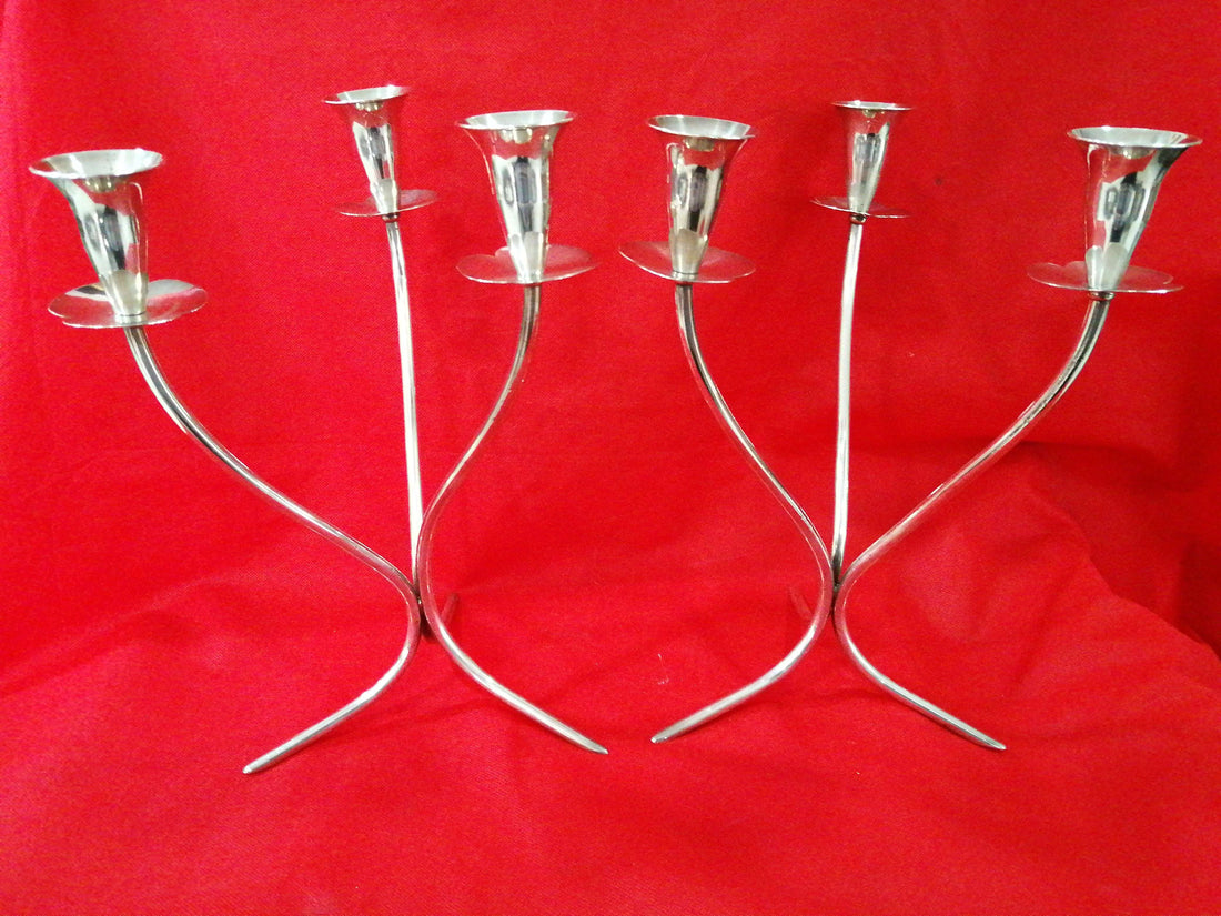 Pareja de candelabros de alpaca de 33 cm con diseño curvo y elegante sobre fondo rojo. Decoración ideal para espacios sofisticados y modernos.