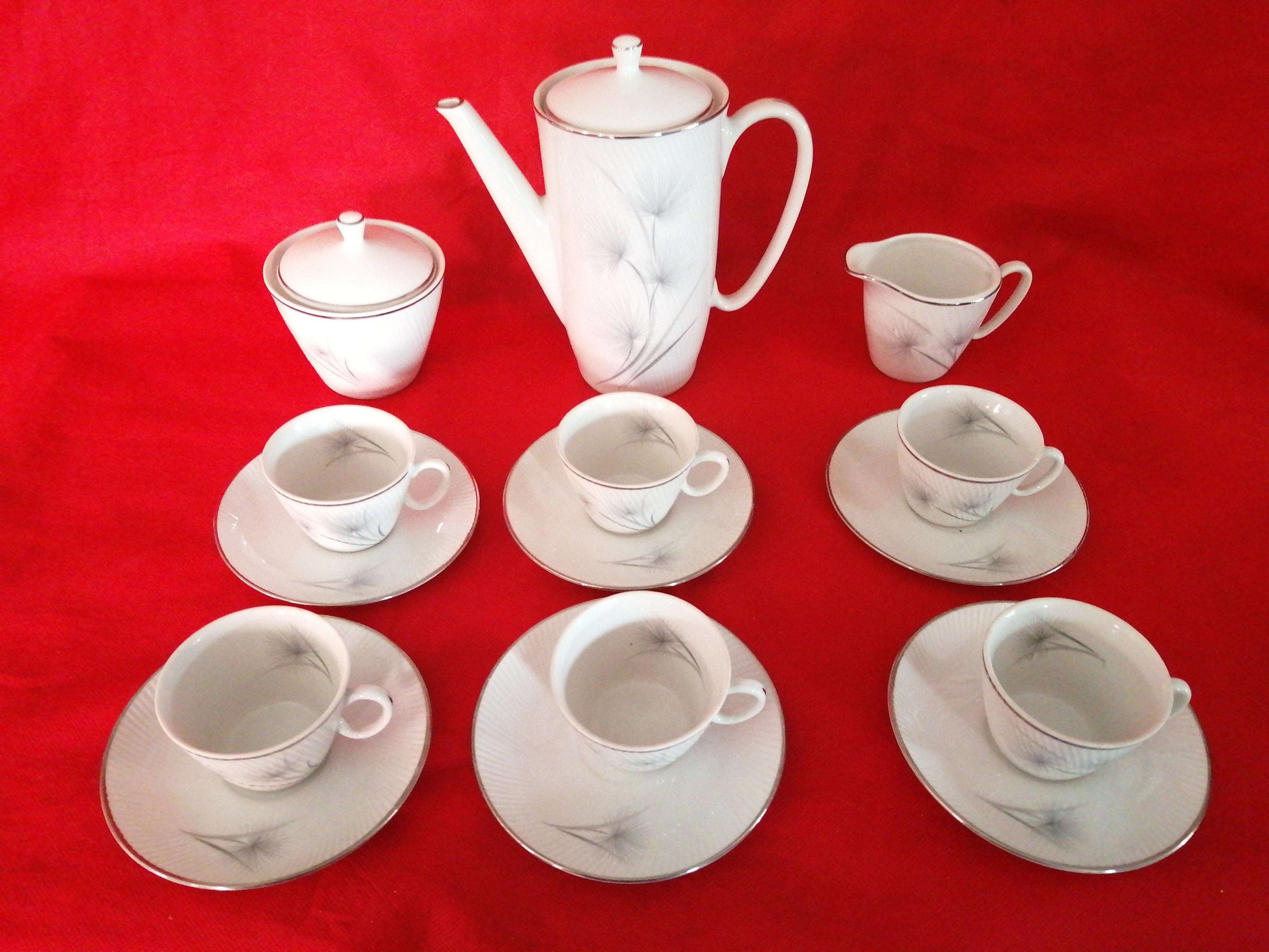 Juego de café porcelana Santa Clara 6 servicios con diseño elegante sobre fondo rojo. Ideal para decoración clásica en el hogar.