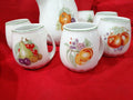 Juego de jarra y jarritas de porcelana Sanbo de alta calidad con diseño de frutas sobre fondo blanco, ideal para decoración clásica del hogar.