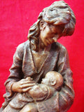 Figura de maternidad en resina firmada, mostrando a una madre amamantando a su bebé. Decoración emotiva de alta calidad para el hogar.