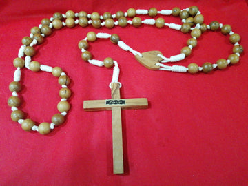 Rosario antiguo de madera con cuentas grandes y cruz tallada, ideal para decoración y oración. Diseño clásico sobre fondo rojo.