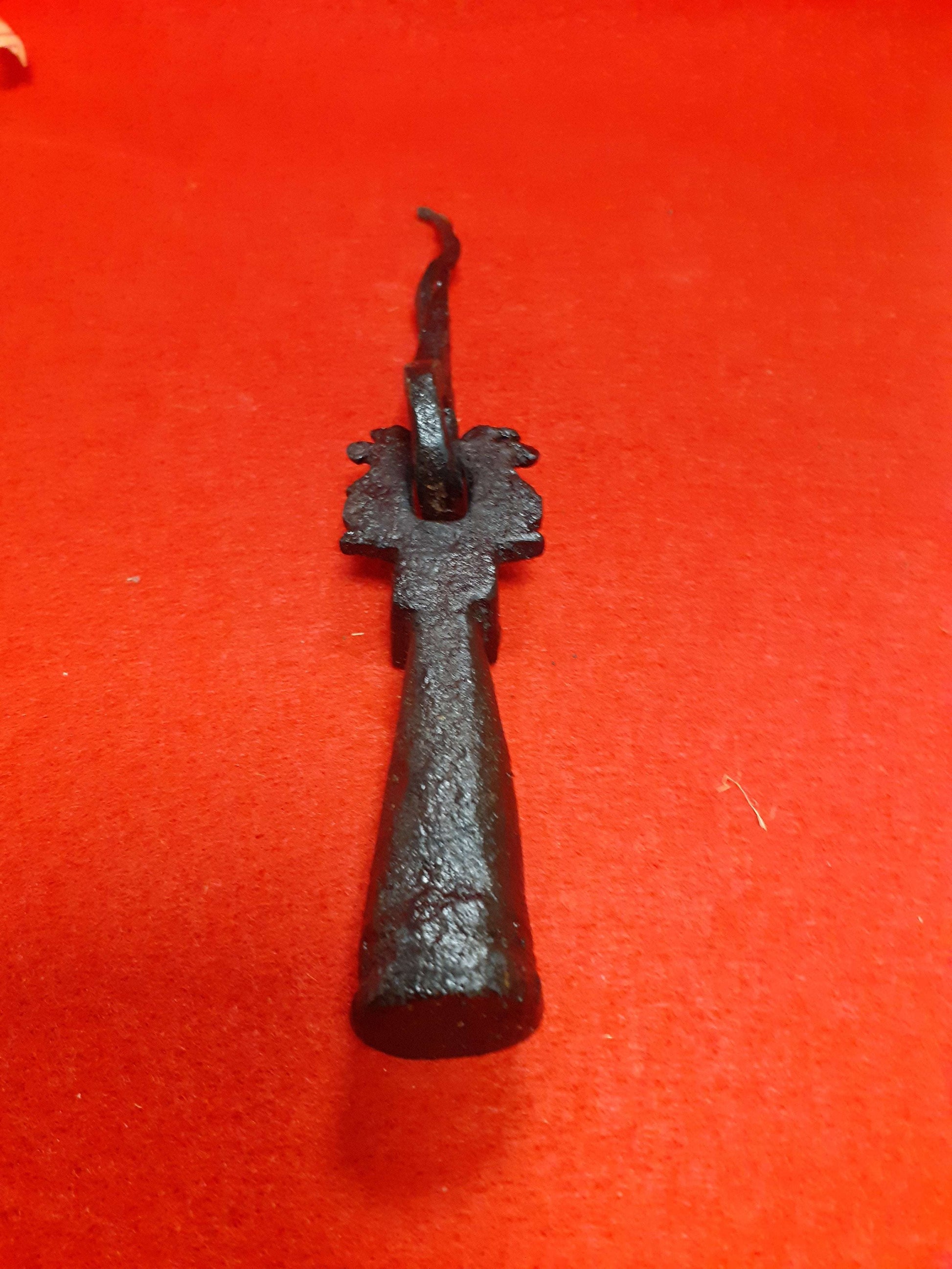 Aldaba-llamador de puerta antiguo S. XVIII en hierro forjado sobre fondo rojo, ideal para decoración clásica en el hogar.