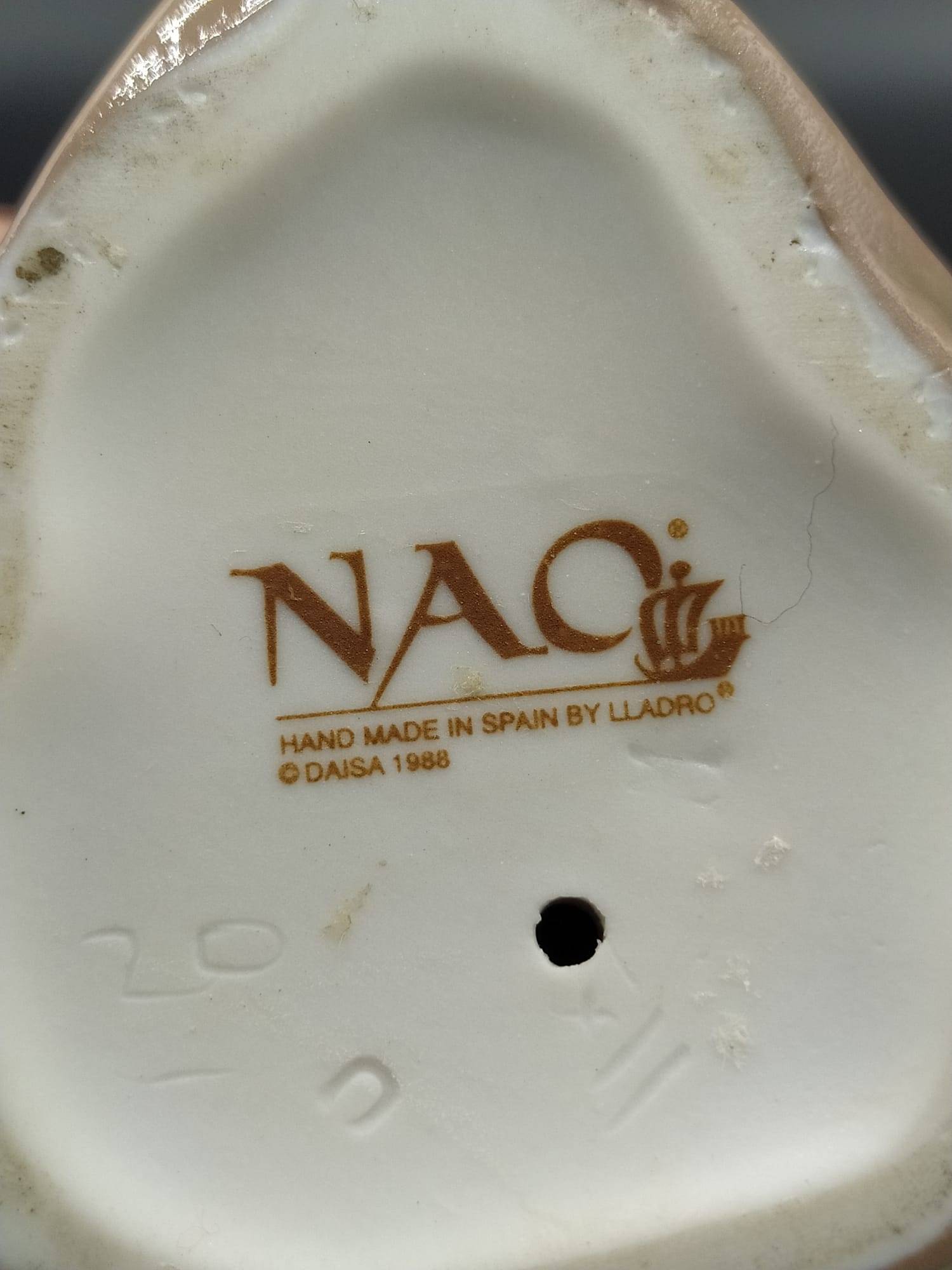 Sello inferior de la figura de porcelana Lladró 'Chica con gorro', marca NAO hecha en España por Lladró, autenticidad para decoración de colección.