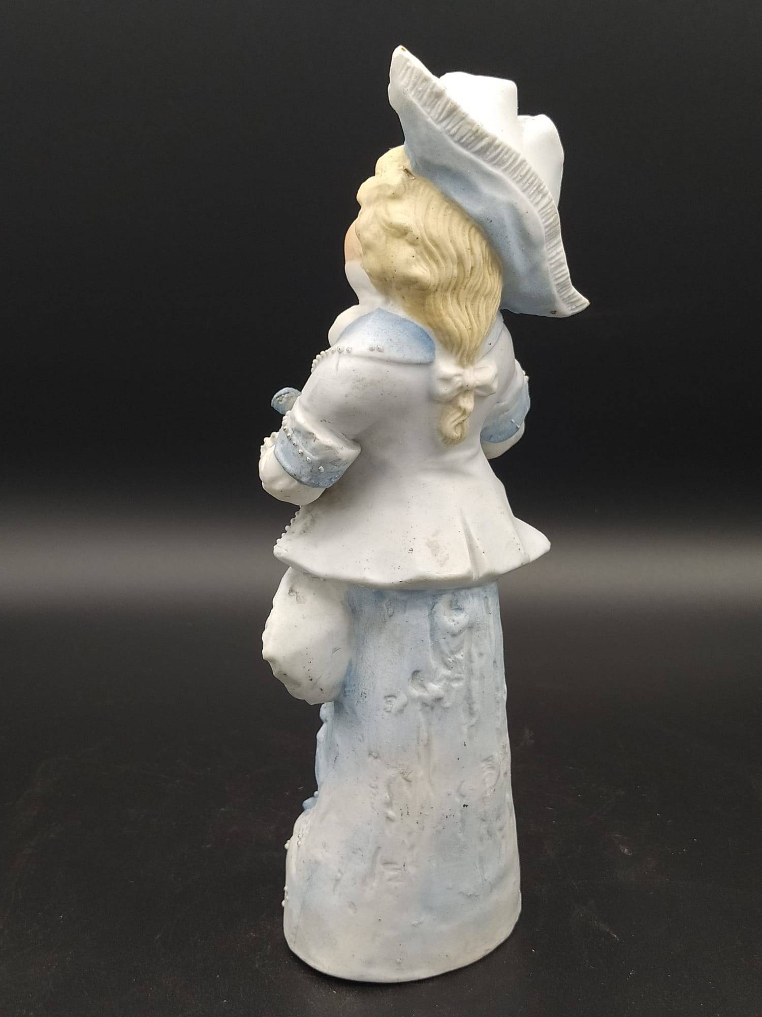 Vista trasera de figura de porcelana antigua de galleta, niño con sombrero y cabello rubio, ideal para decoración clásica.