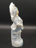 Figura decorativa de porcelana galleta, niño con traje azul y sombrero, sosteniendo instrumento de cuerda, estilo antiguo.