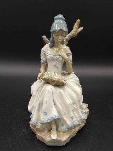 Figura de porcelana Mujer con Flores de Casades sentada con vestido blanco y detalles florales, ideal para decoración elegante de interiores.