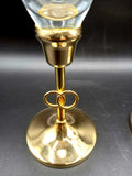 Detalle de copa de champán de cristal tallado con base dorada y anillos entrelazados, diseño elegante con oro de 24K para decoración de bodas.