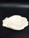 Jabonera en cerámica con diseño de manos blancas, ideal para decoración de baño o cocina. Calidad única y estilo artesanal elegante.