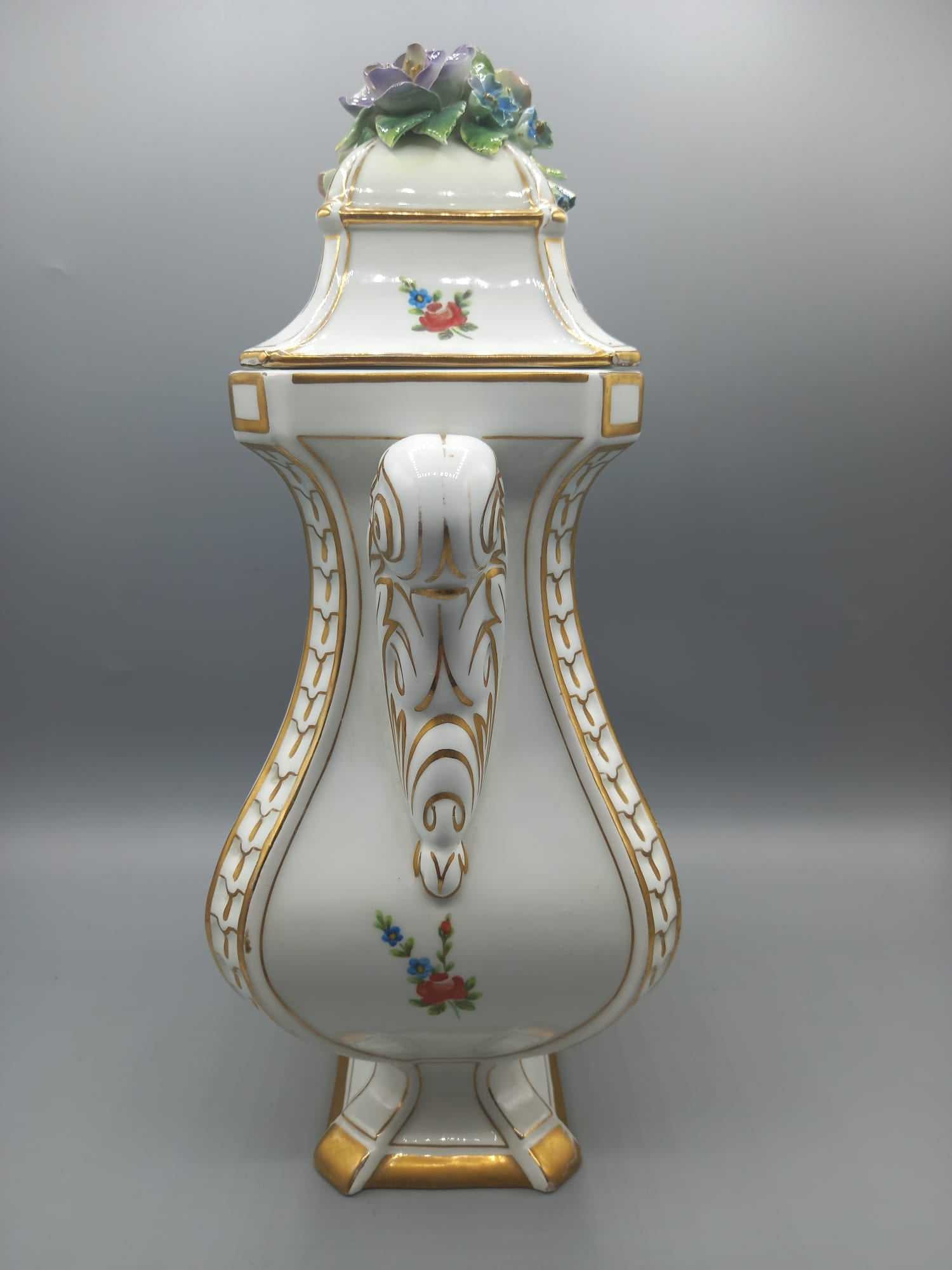 Jarrón de porcelana pintado con detalle floral, calidad superior, con tapa decorada con flores en relieve y bordes dorados, estilo antiguo.
