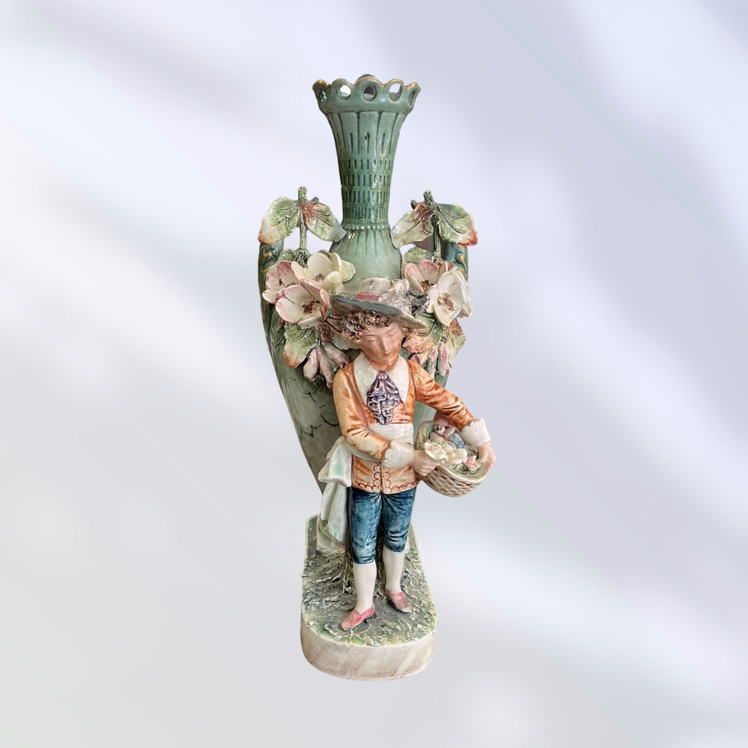 Florero de porcelana pintado a mano con figura de campesino, detalles florales y diseño artístico inspirado en el siglo XIX.