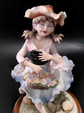 Primer plano de la figura de porcelana Carlos de niña con vestido azul y sombrero, expresión dulce y diseño floral detallado.