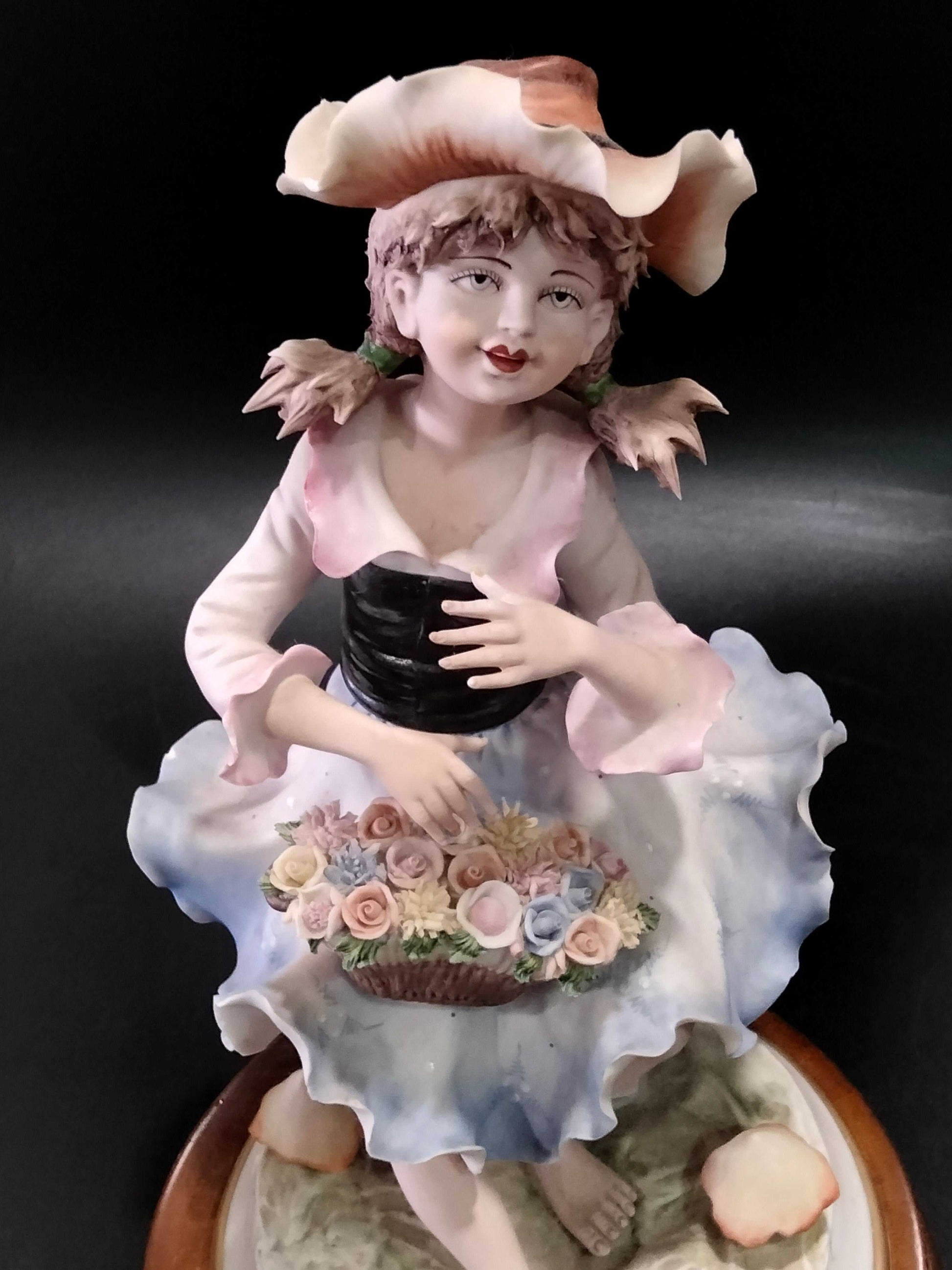 Primer plano de la figura de porcelana Carlos de niña con vestido azul y sombrero, expresión dulce y diseño floral detallado.