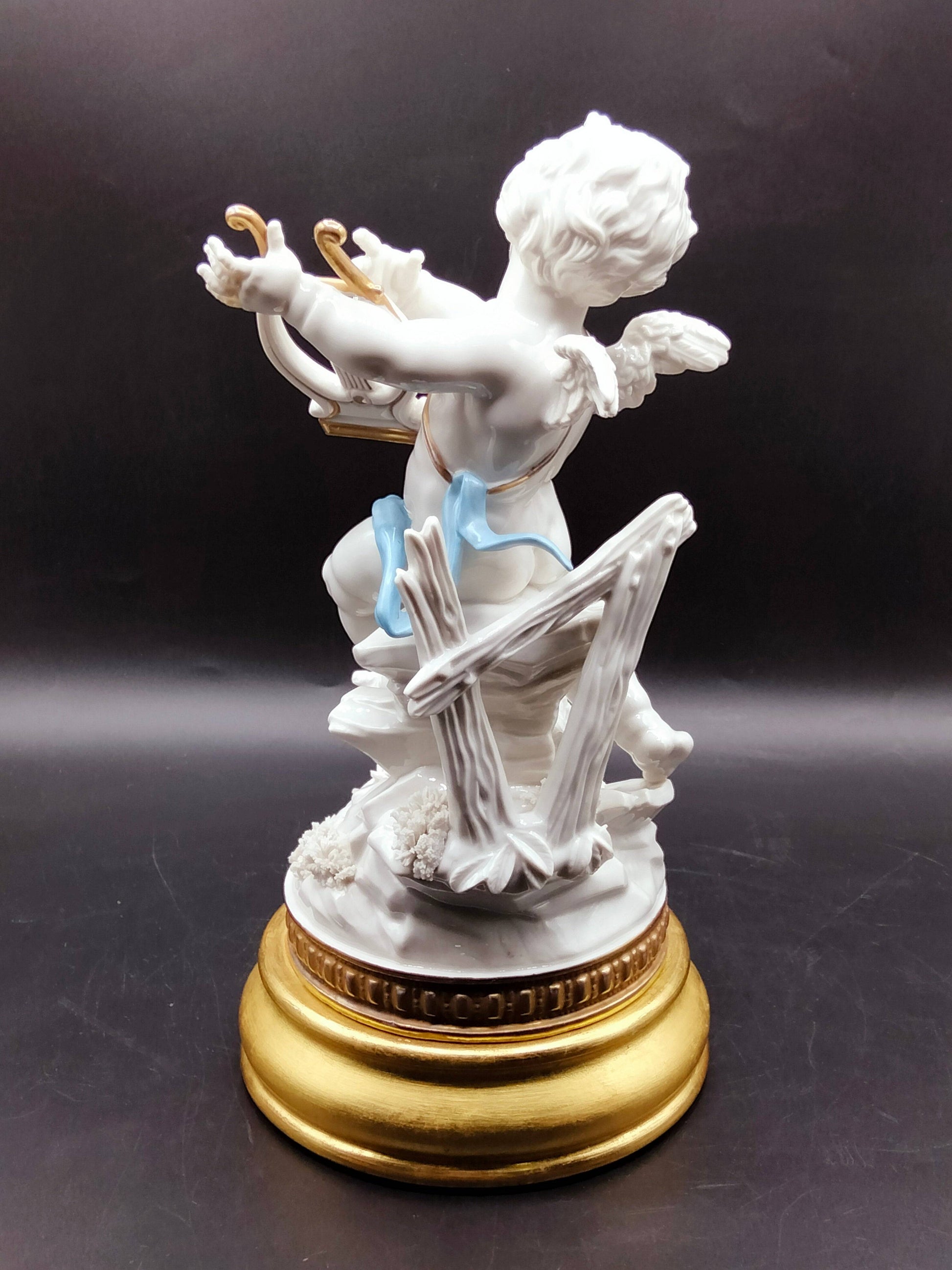 Figura clásica de porcelana Angél Algora con arpa, vista trasera mostrando alas y detalles en madera, decoración única para interiores refinados.