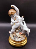 Figura decorativa Ángel con Pato de porcelana Algora, ángel infantil con expresión viva y pato en movimiento sobre peana dorada.