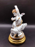 Figura de porcelana Ángel con Pato - Elegancia y Lujo | Decoración, con ángel alado y pato detallado en escena dinámica sobre base dorada.