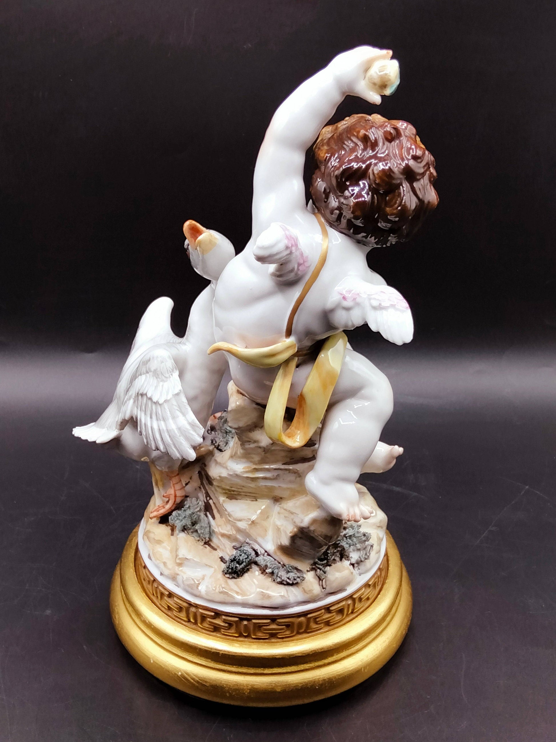 Vista trasera de la figura Ángel con Pato en porcelana, destacando detalles del ala, cabello rizado y base decorativa dorada de lujo.