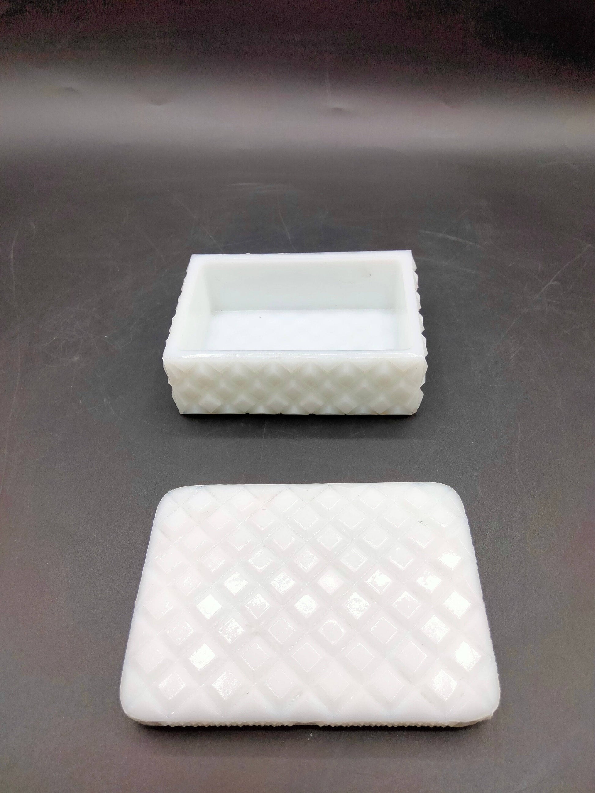 Caja joyero de opalina blanca con diseño en rombos, abierta con tapa al lado. Perfecta para guardar joyas con estilo clásico.