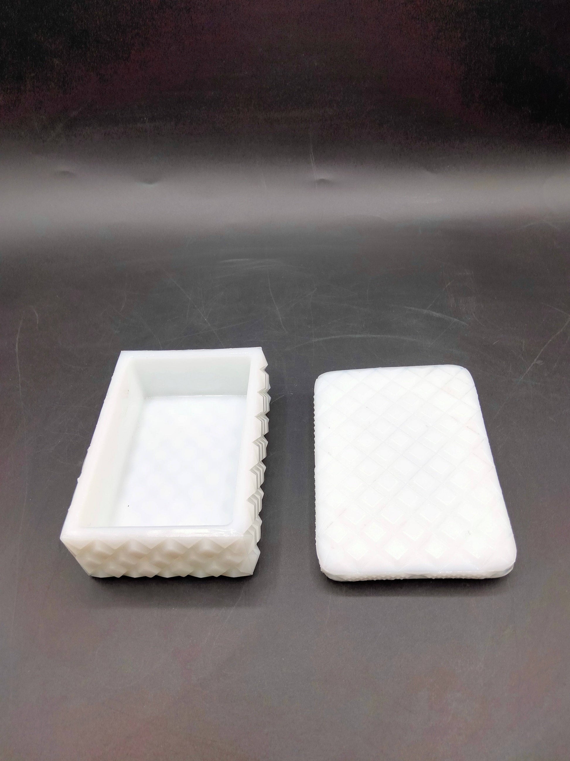 Joyero rectangular de opalina blanca con patrón de rombos, tapa removida mostrando interior espacioso. Decoración refinada para el hogar.