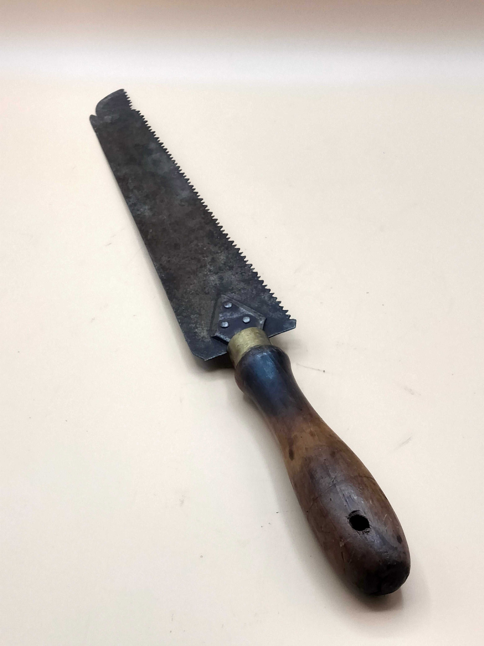 Sierra de mano antigua para carpintería con mango de madera oscura y hoja metálica dentada, ideal para decoración vintage en hogar y jardín.